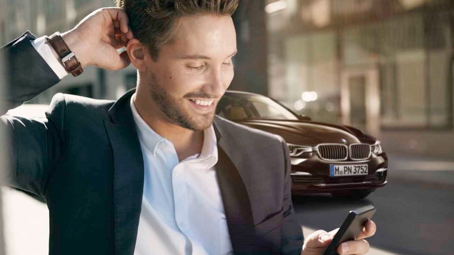 Mann, Straße, Auto im Hintergrund, Handy, BMW Beratung, kontaktlose Beratung 